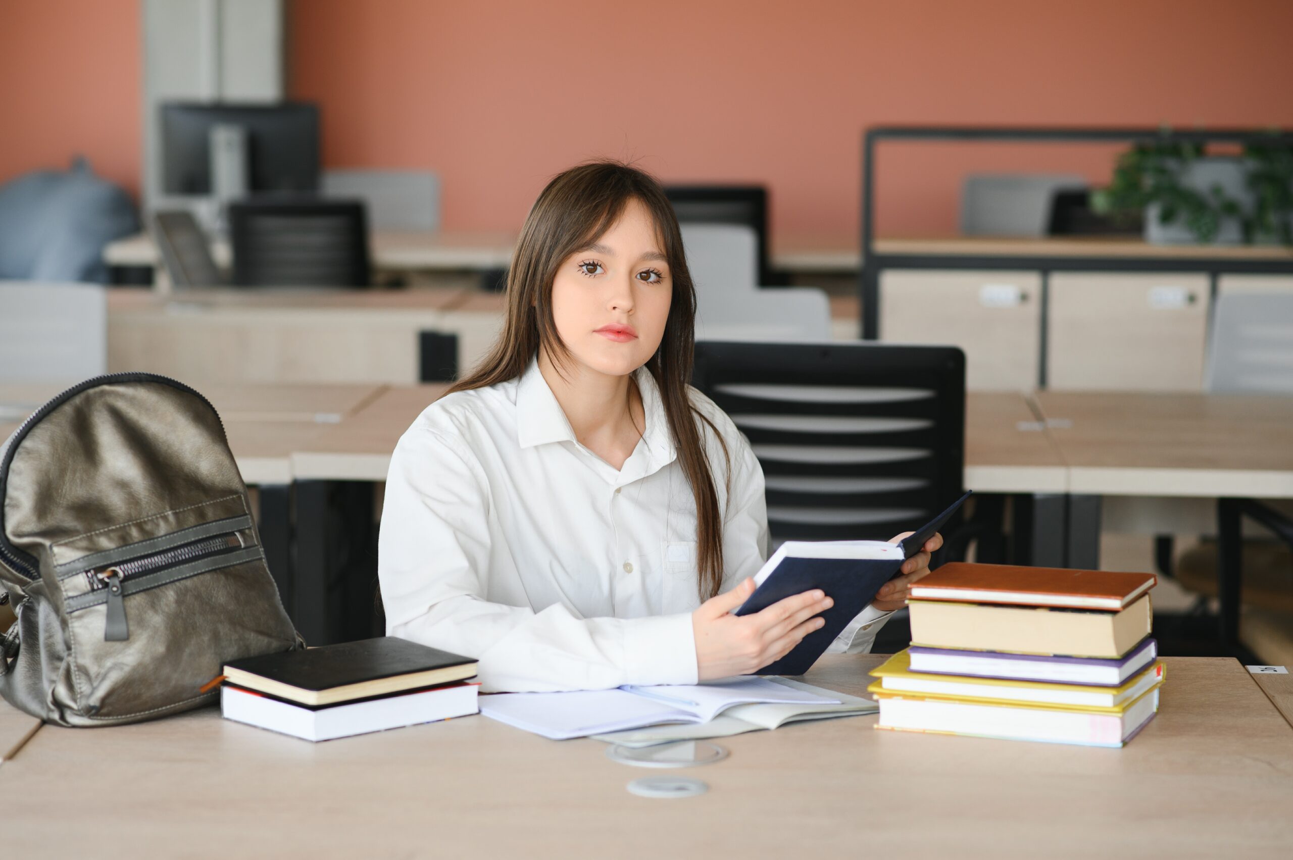 teen girl studying with textbook writing essay learning classroom scaled